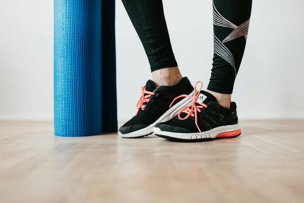 Close-up of athletic shoes on a dark yoga mat, suggesting balance and stability.